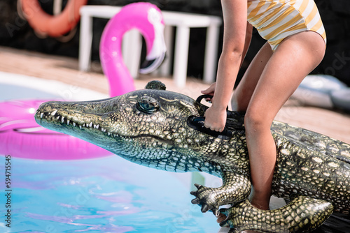 Crop kid on inflatable crocodile in pool photo