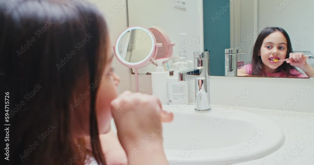 Little cute girl brushes her teeth in the bathroom in the morning. I keep my teeth strong. cheerful girl first grader brushes her teeth and looks at her reflection in the mirror, in bathroom at home. Little cute girl brushes her teeth in the bathroom in the morning. I keep my teeth strong. cheerful girl first grader brushes her teeth and looks at her reflection in the mirror, in bathroom at home.