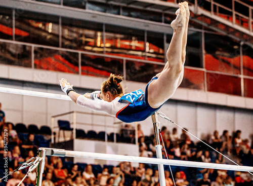 flight element from low bar to high bar female gymnast exercise on uneven bars in artistic gymnastics photo