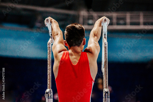 Фотография rear view athlete gymnast begin exercise parallel bars in championship gymnastic