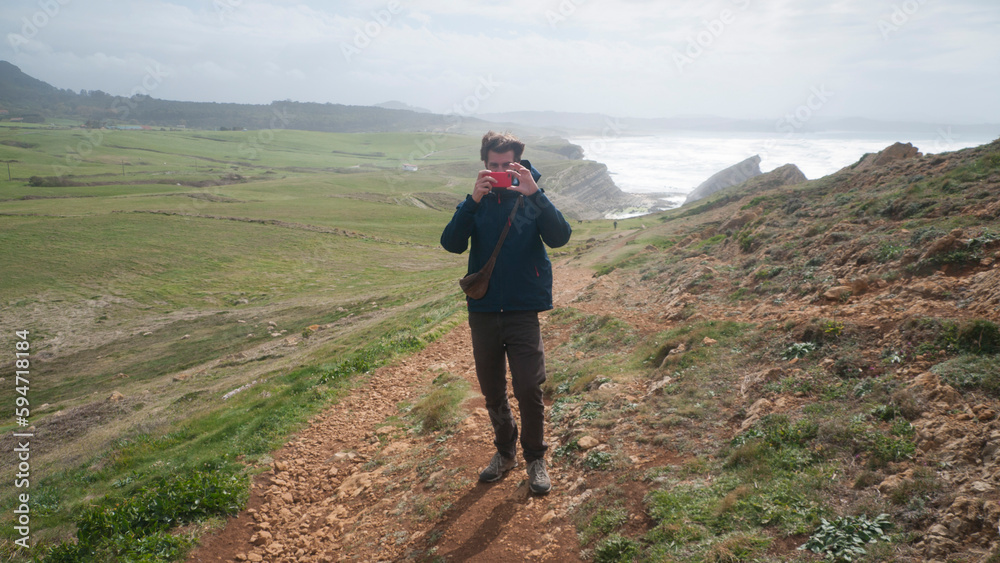 Hombre haciendo una foto a cámara en paisaje rocoso junto al mar