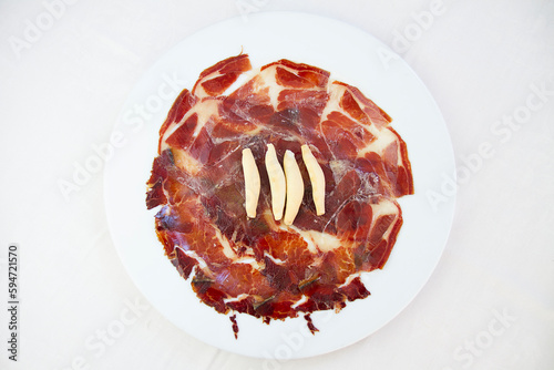 Spanish iberian cured ham with breadsticks on white plate photo