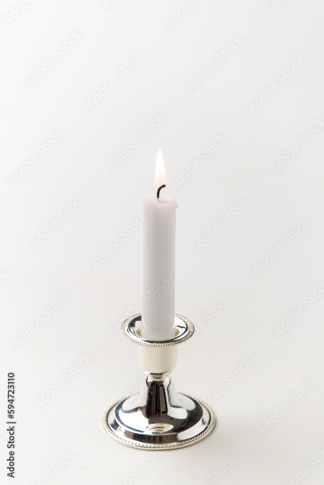 burning candle inside silver candlestick on a white background metallic lamp steel flame burning candle inside silver candlestick on a white background metallic lamp steel flame