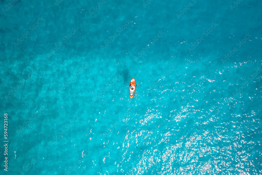Photo en drone d'une femme sexy sur un paddle dans une eau bleu turquoise