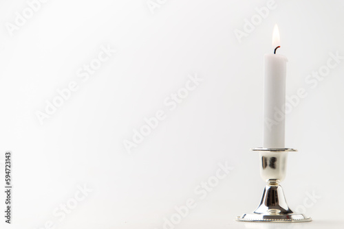 burning candle inside silver candlestick on a white background steel metallic lamp flame