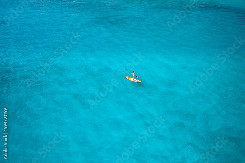 Photo en drone d'une femme sexy sur un paddle dans une eau bleu turquoise