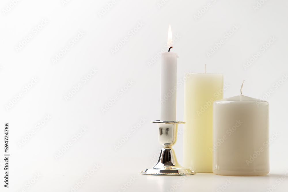 burning candle with other candles on a white background metallic lamp steel flame fire burning candle with other candles on a white background metallic lamp steel flame fire
