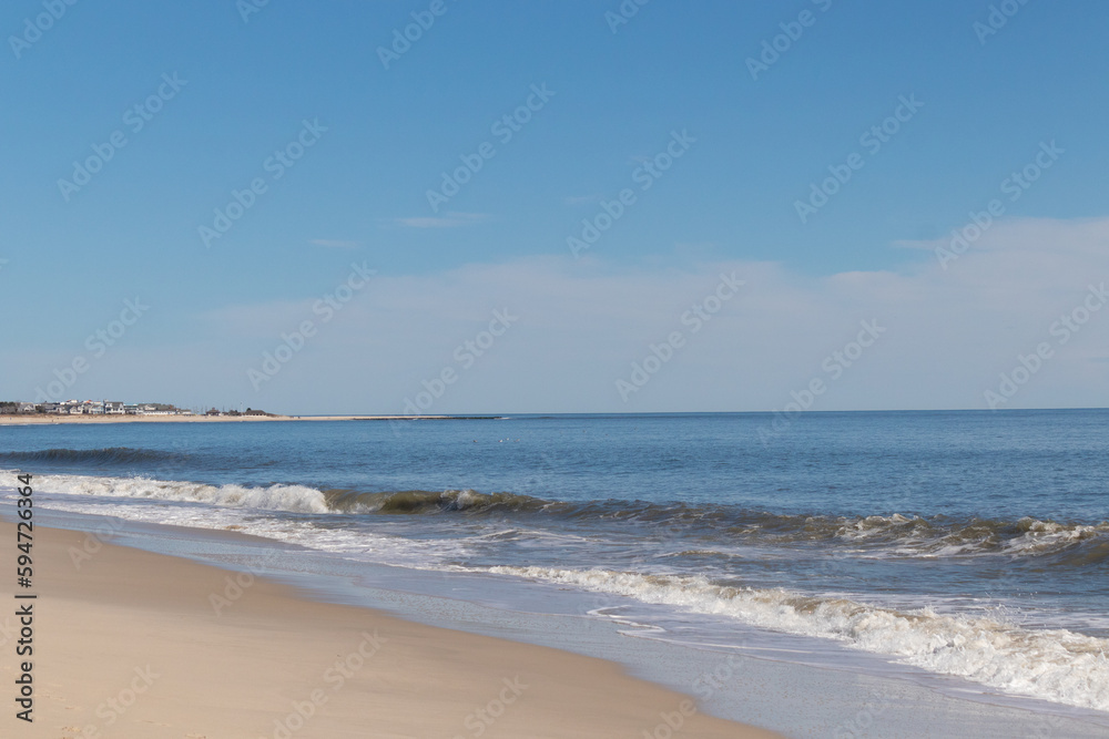 This beautiful beach image was taken at Cape May New Jersey. It shows the waves rippling into the shore and the pretty brown sand. The blue sky with the little bit of cloud coverage adds to this. This beautiful beach image was taken at Cape May New Jersey. It shows the waves rippling into the shore and the pretty brown sand. The blue sky with the little bit of cloud coverage adds to this.