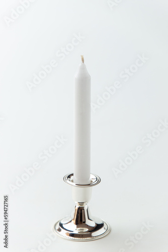 white candle inside silver candlestick on the white background flame lamp fire steel metallic
