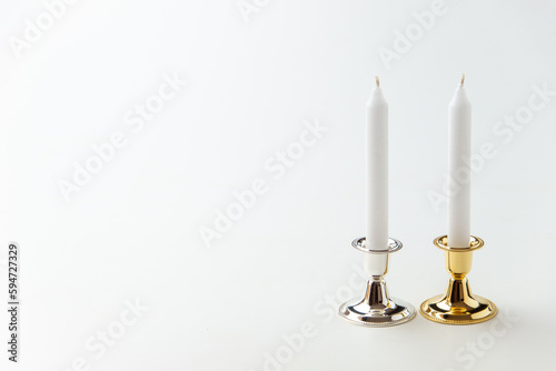 white candles inside elegant candlesticks on the white background flame lamp fire steel metallic