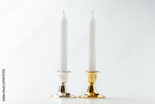 white candles inside elegant candlesticks on white background flame lamp steel metallic