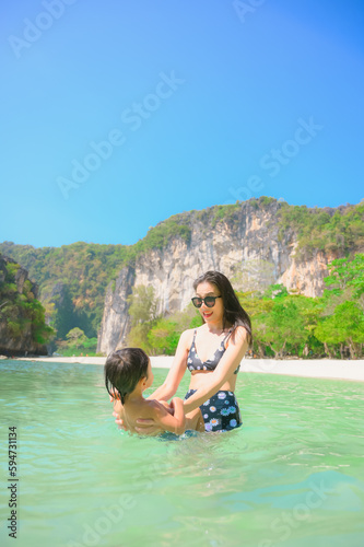 Happy mother and son resting at beach in summer, Krabi, Thailand