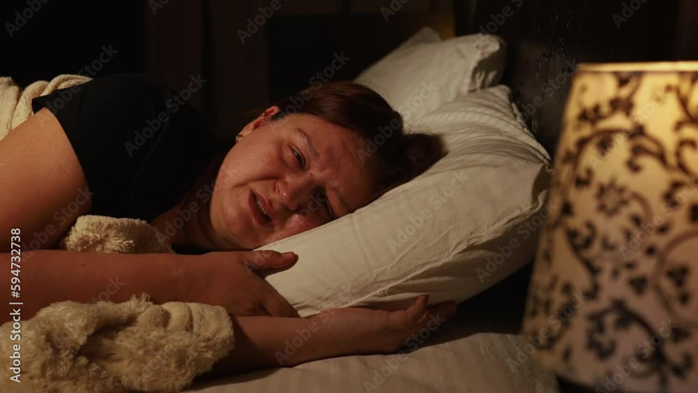 Upset woman lie on pillow in bed and cry in dark bedroom. Calm down and try asleep. Person with tearful eyes and swollen face. Emotional breakdown, stress. Depression, night hysterics before sleep. Upset woman lie on pillow in bed and cry in dark bedroom. Calm down and try asleep. Person with tearful eyes and swollen face. Emotional breakdown, stress. Depression, night hysterics before sleep.