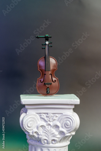 violin miniature perched on a Roman column macro photography