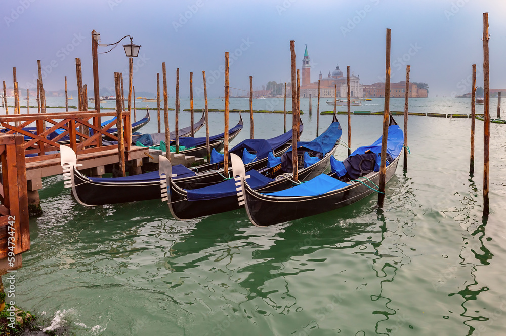 Traditional gondolas at the pier with the island of San Maggiore in the background.
