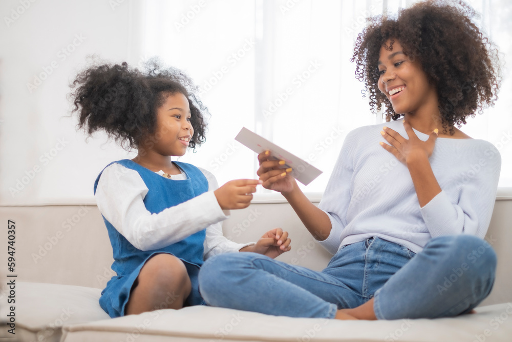 African American daughter give her mother mother's card to with mom surprising emotion, expresstion, in mother,s day ocasionary, love happiness feeling in picture. African American daughter give her mother mother's card to with mom surprising emotion, expresstion, in mother,s day ocasionary, love happiness feeling in picture.