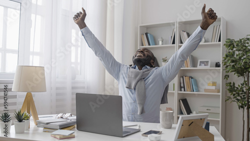 Excited African American male businessman celebrating good news after reading e-mail on laptop