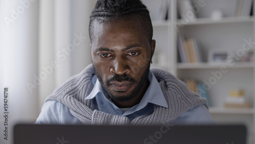 Male freelancer working on laptop  attentively looking at display at home office