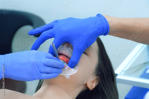 Orthodontist is fixing metal part on woman's patient teeth preparing to condylography. Examination and treatment of mandibular joints. Orthodontology treatment and cure concept. Dentistry and clinic. photo