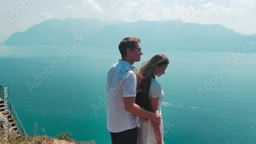 Summer. Young couple in love on top of a mountain in front of a blue lake