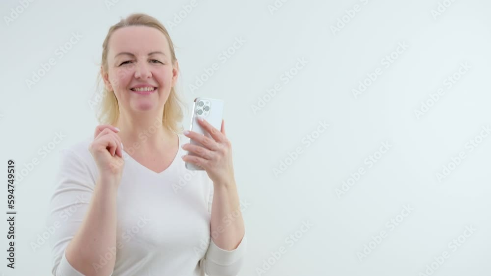 Beautiful yuong woman dance on white background, pretty dancer. a woman on a white background in her hands with a phone dancing rejoices typing text spend a nice time having fun good news joy Beautiful yuong woman dance on white background, pretty dancer. a woman on a white background in her hands with a phone dancing rejoices typing text spend a nice time having fun good news joy