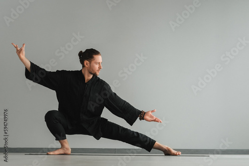 A man in black kimano practicing qigong energy exercises indoors photo