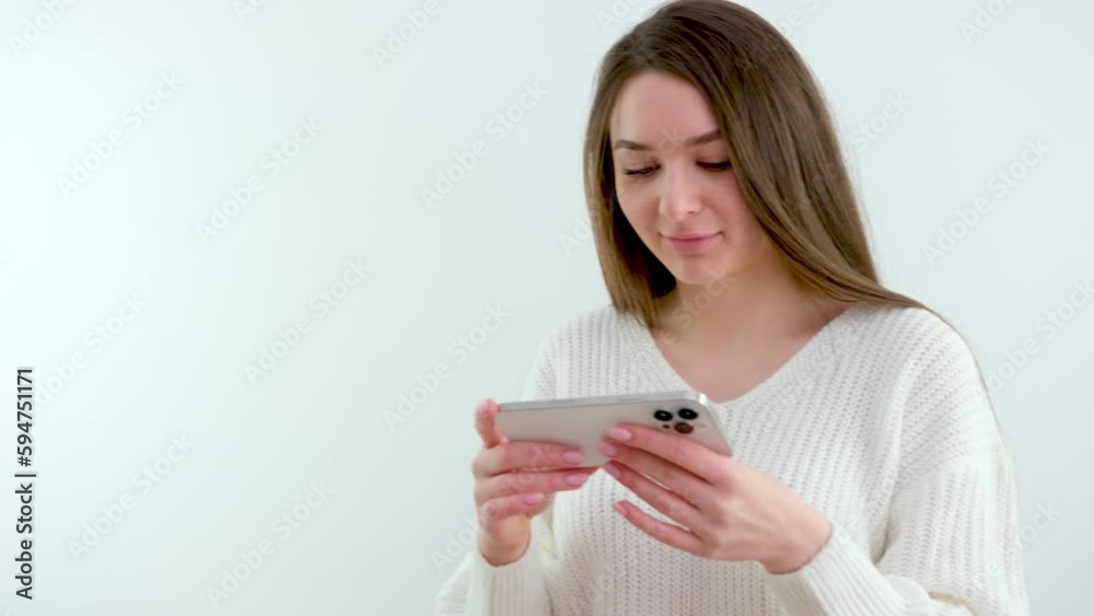 beautiful young girl holding a phone in her hands horizontally gentle manicure Light clothes white background advertising smile The very charm of a beautiful woman Woman using a smart phone beautiful young girl holding a phone in her hands horizontally gentle manicure Light clothes white background advertising smile The very charm of a beautiful woman Woman using a smart phone