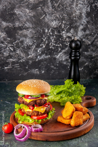 Tasty homemade sandwich tomatoes pepper on cutting board onions tomato with stem chicken nuggets on dark color background with free space photo