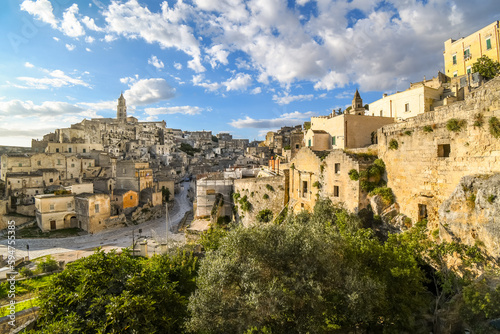 Hillside view of the ancient city of Matera  Italy in the Basilicata region  including the old town  tourist street and mountain path  Sasso Barisano tower and the steep ravine canyon below.
