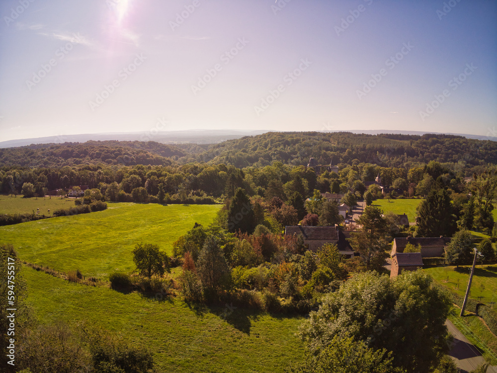 Drone photo of houses between trees and mountains in Belgium, beautiful horizon view