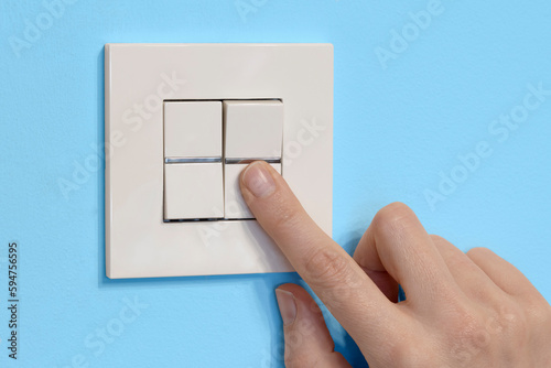 dedo pulsando el interruptor de la luz sobre fondo azul