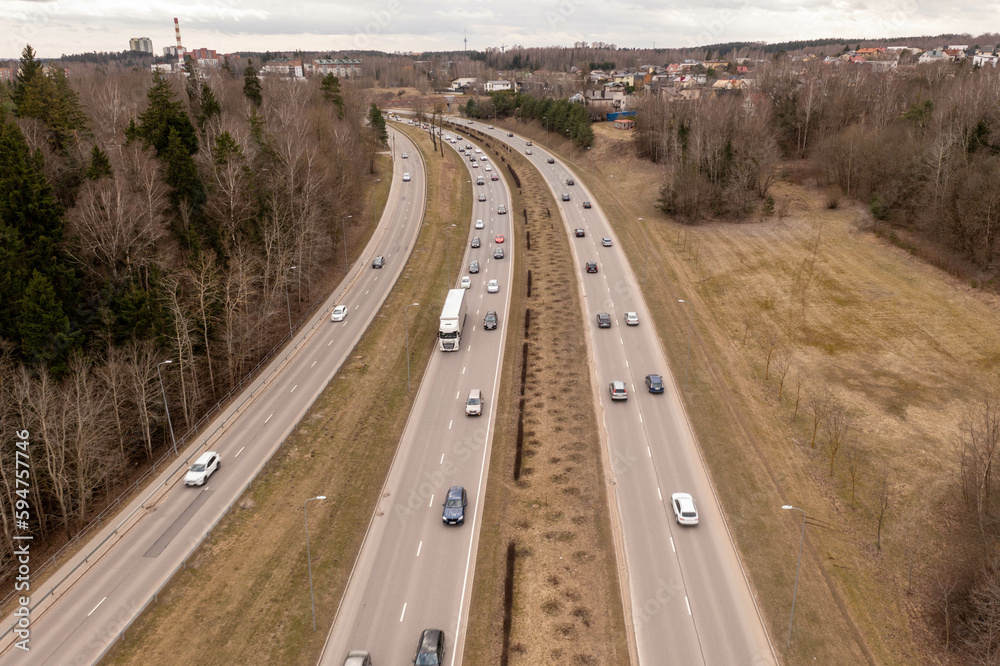 Drone photography of major highway in a city and traffic during springtime day.