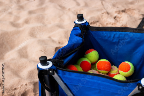 Basket of beach tennis balls on the sand - copy space
