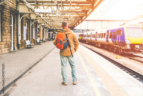 Traveler with a backpack waiting for a train at the train station. Travel concept.