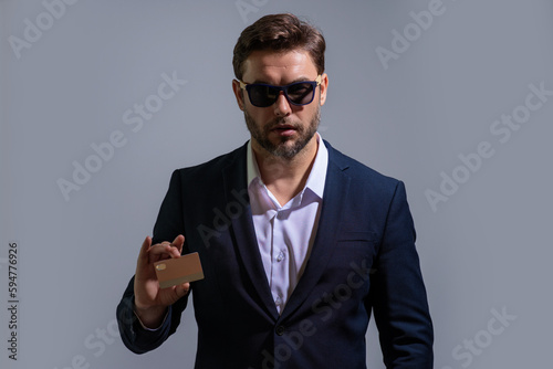 Business man holding a credit card on gray isolated background. Hispanic man showing credit card. Credit or deposit bank card. Online shopping concept. Offer discount sale, online shopping.