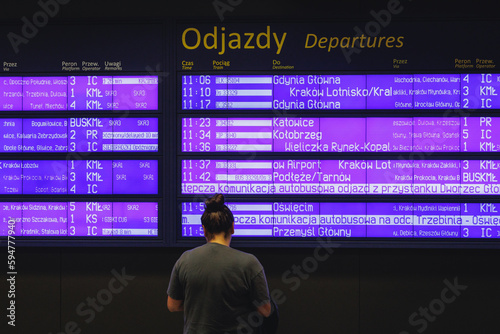 Passenger in front of timetable on railway station in Krakow, Poland