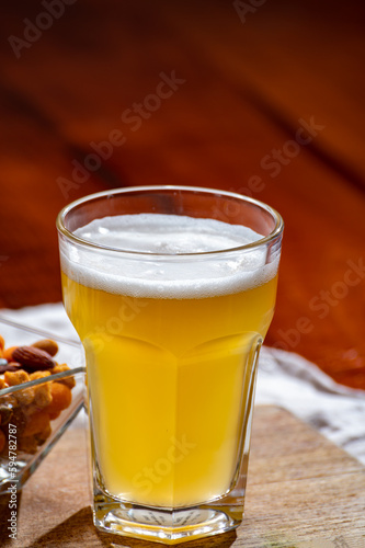 Glass of Belgian white unfiltered beer with notes of coriander and orange peer and different snack nuts