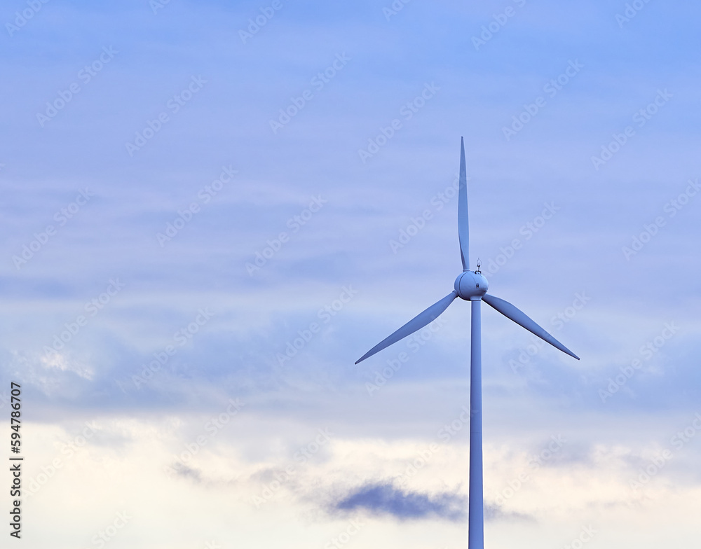 A beautiful shot of a wind turbine with rotating blades on a cloudy day