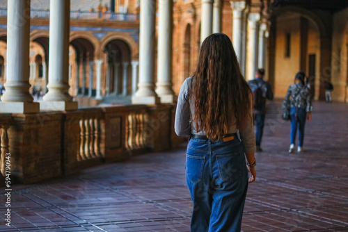 Back view of a young woman visiting Spain Square (Plaza de Espana). Seville tour. Spanish Square, a beautiful famous tourist place.