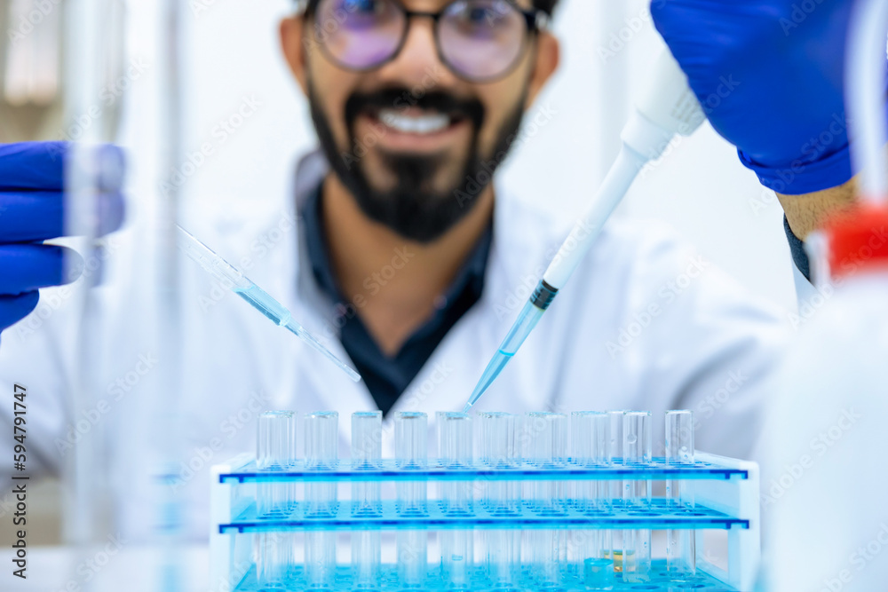 Male scientist using pipette and glass-dropper with flask in medical science laboratory Male scientist using pipette and glass-dropper with flask in medical science laboratory