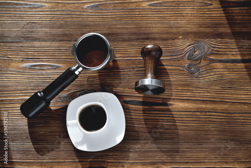 a cup of coffee, a coffee horn and a tamper on a wooden background, selective focus photo
