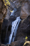 The cave waterfall in the heart of the National Park of Ordesa and Monte Perdido, set in a rocky canyon, branches and small tree with autumn colored leaves