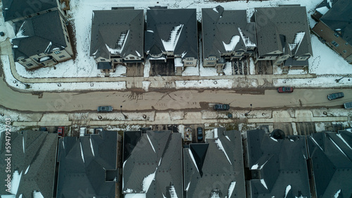 Looking down from an aerial view at houses, streets and backyards in the suburbs during winter