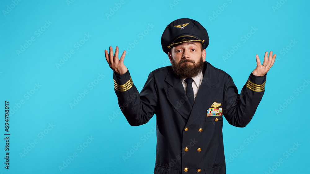 Clueless flying pilot doing i dont know gesture, acting uncertain and doubtful over blue background. Professional aviator feeling unsure and raising shoulders on camera, aircraft captain. Clueless flying pilot doing i dont know gesture, acting uncertain and doubtful over blue background. Professional aviator feeling unsure and raising shoulders on camera, aircraft captain.