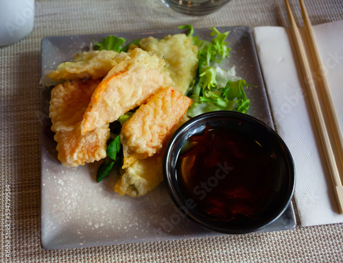 Closeup of tasty fried vegetable tempura served with lettuce  sauce and chopsticks..