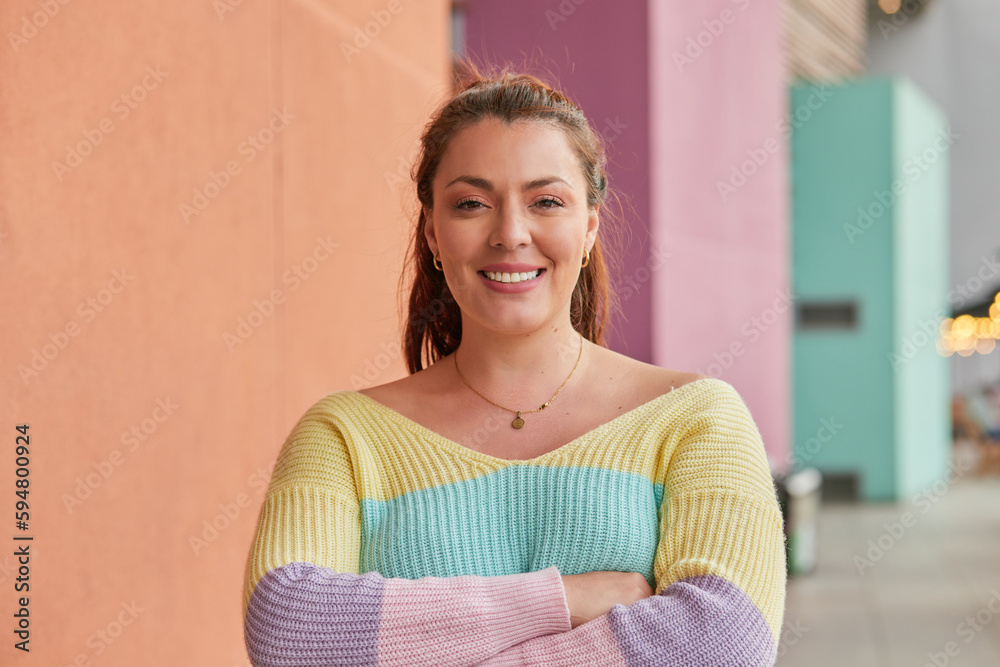 Smiling woman in pastel sweater poses with arms crossed Smiling woman in pastel sweater poses with arms crossed