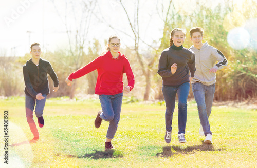 Cheerful teenagers are jogging together in the park and having fun