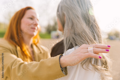 An adult daughter strokes the hair of an elderly gray-haired mother. The concept of caring for an elderly mother and intergenerational relationships