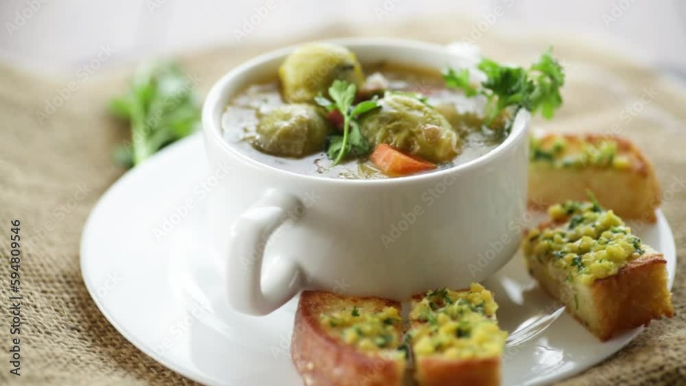 Hot cooked soup with Brussels sprouts, vegetables and croutons, in a plate.