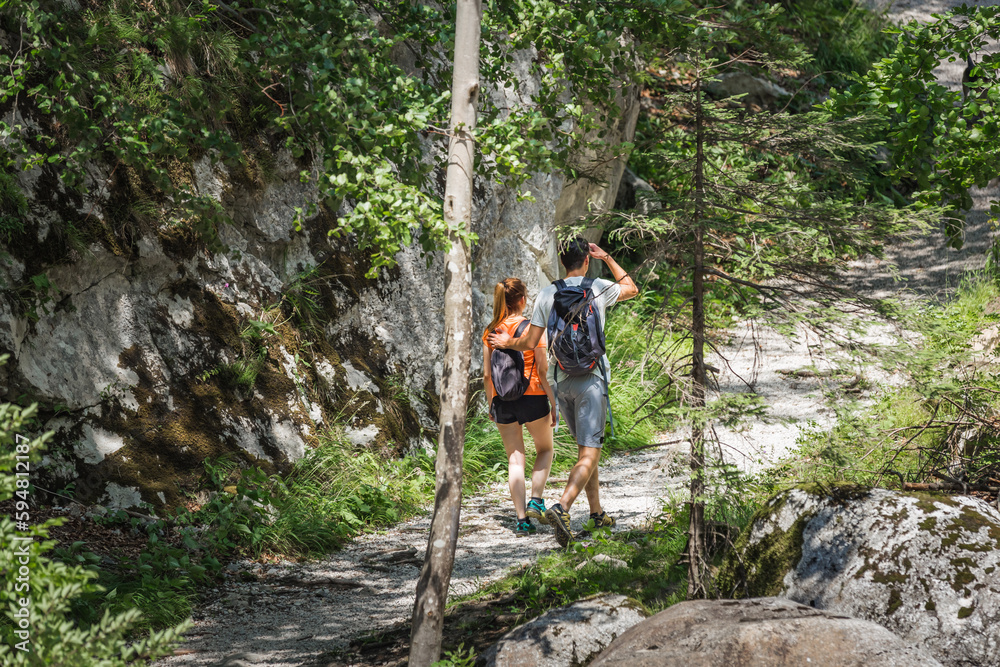 Two young hikers with backpacks, a couple in love exploring nature
